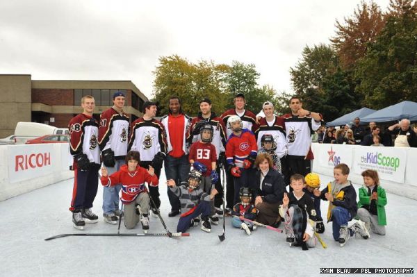 A group poses with (back row) several members of the Stingers hockey team and Canadiens player Georges Laracque (centre, red t-shirt). President Judith Woodsworth poses in front.